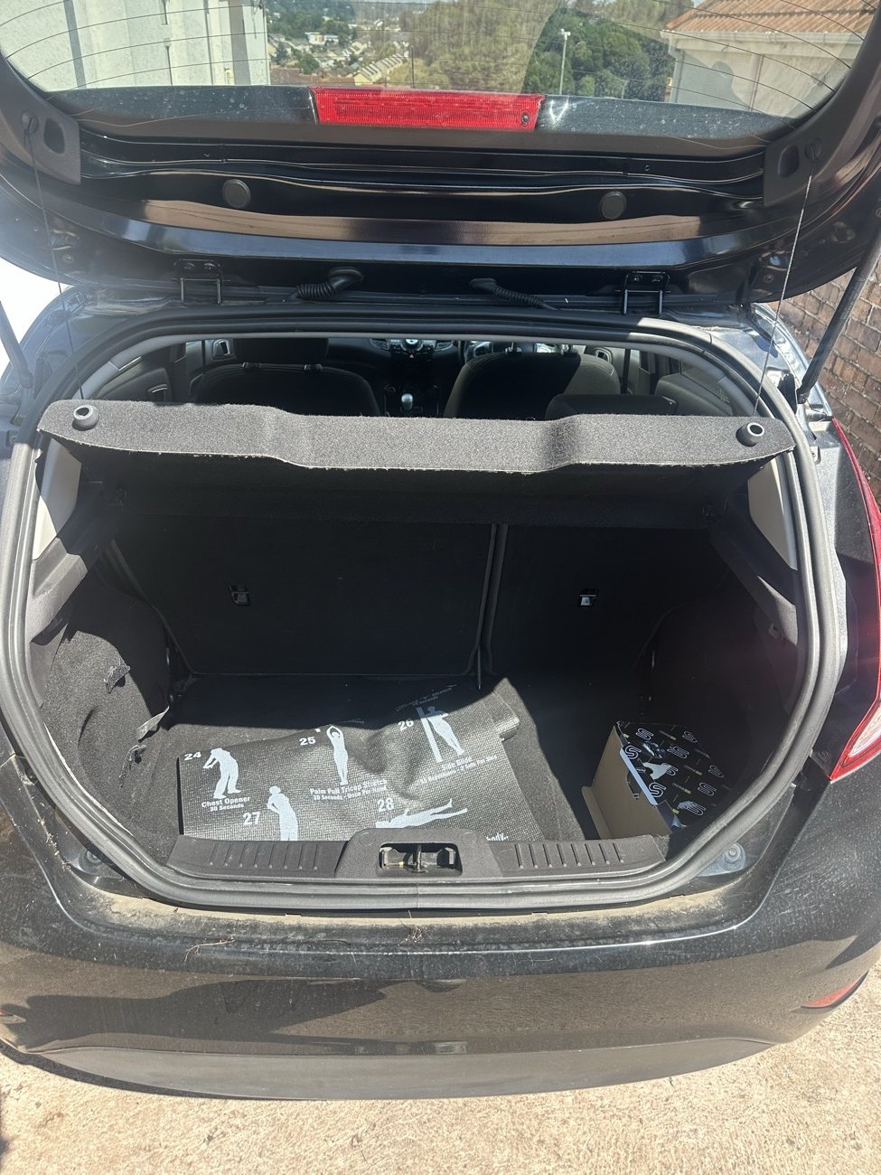 Black Ford Fiesta boot before, floor mat lifted and dusty