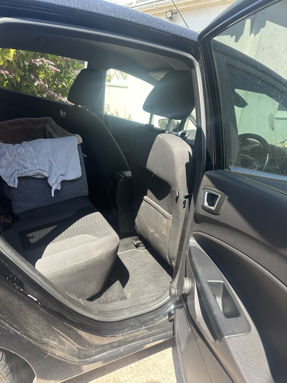 Black Ford Fiesta rear seats before, dusty sill and debris