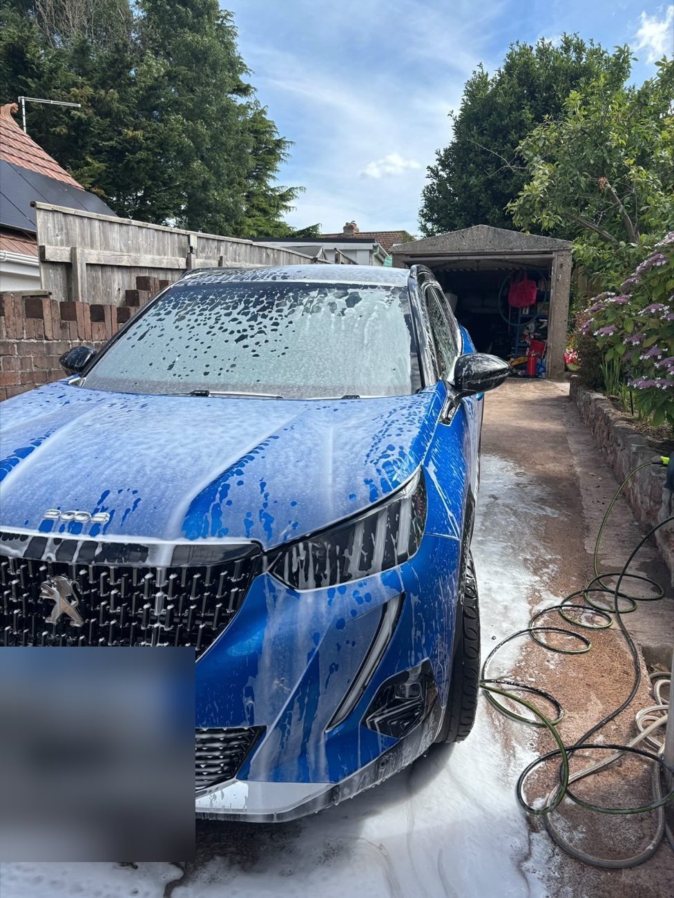 Blue Peugeot 2008 covered in snow foam before rinsing